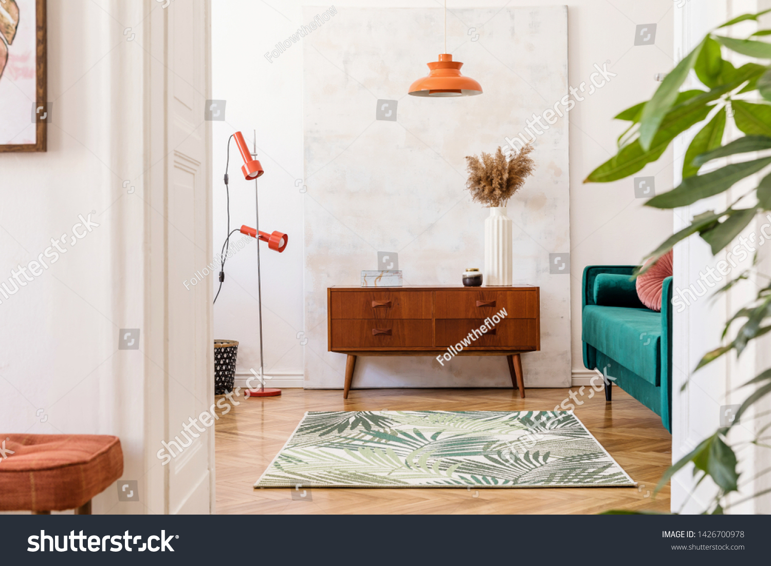 Stylish compositon of retro home interior with vintage cupboard, velvet sofa, flowers in vase, design orange lamps , elegant accessories and abstract paintings. Minimalistic concept. Nice home decor.  #1426700978