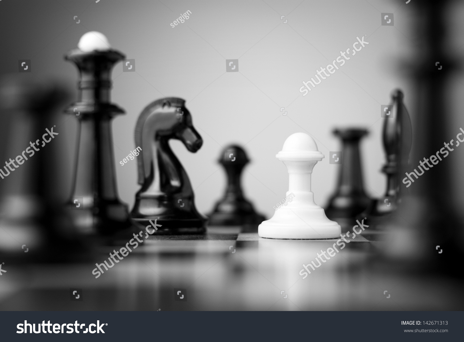 white pawn surrounded by black chess pieces on a chess board #142671313