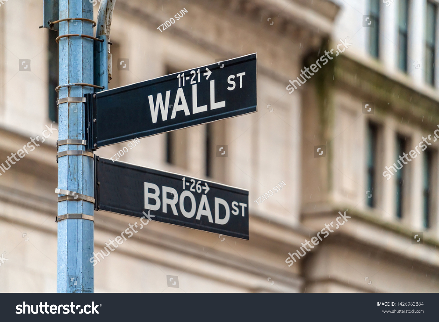 Wall Street "WALL ST" sign and broadway street over  NYSE stock market exchange building background. The New York Stock Exchange locate in economy district, Business and sing of landmark concept #1426983884