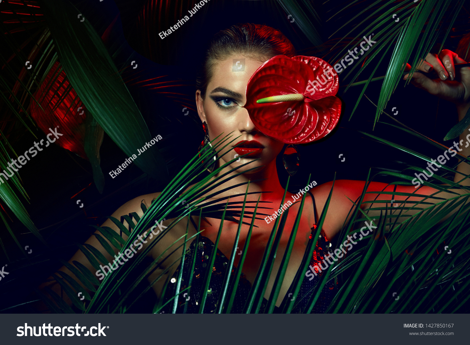 A beautiful tanned girl with natural make-up and wet hair stands in the jungle among exotic plants. #1427850167
