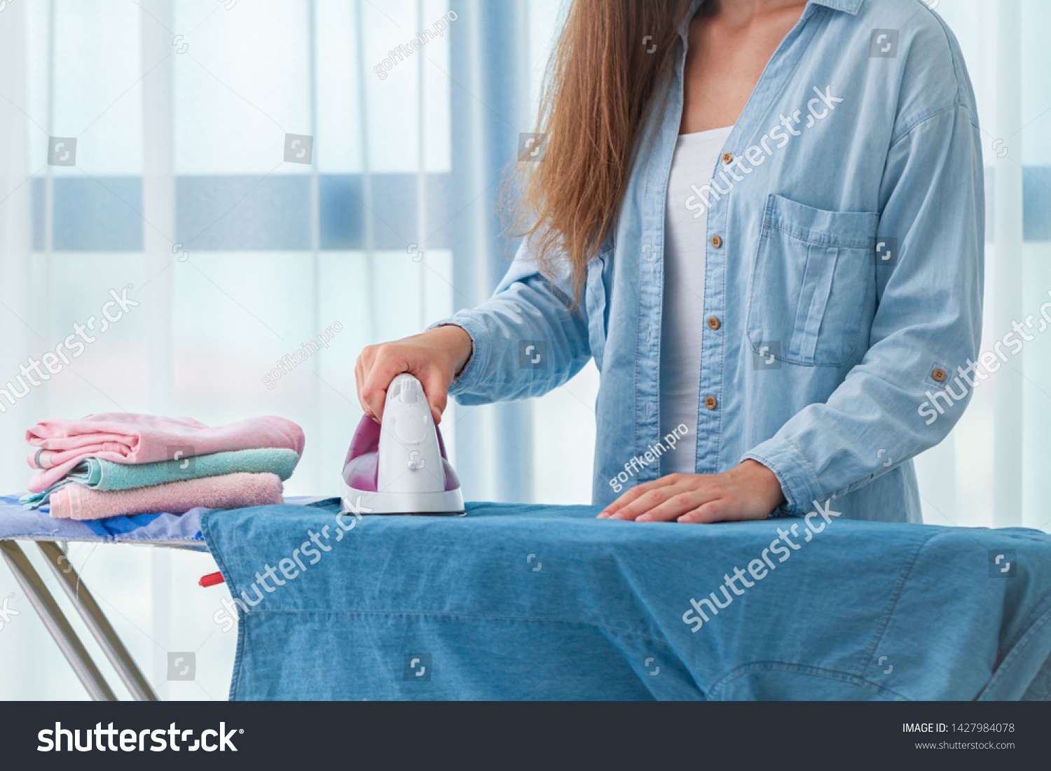 Using iron for ironing clothes after laundry at home  #1427984078
