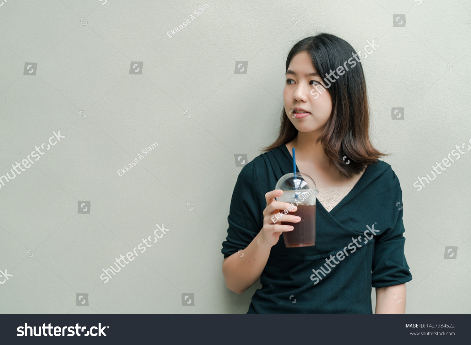Asian beautiful woman Put on a black shirt, stand to drink cold coffee in the hand with pleasure #1427984522