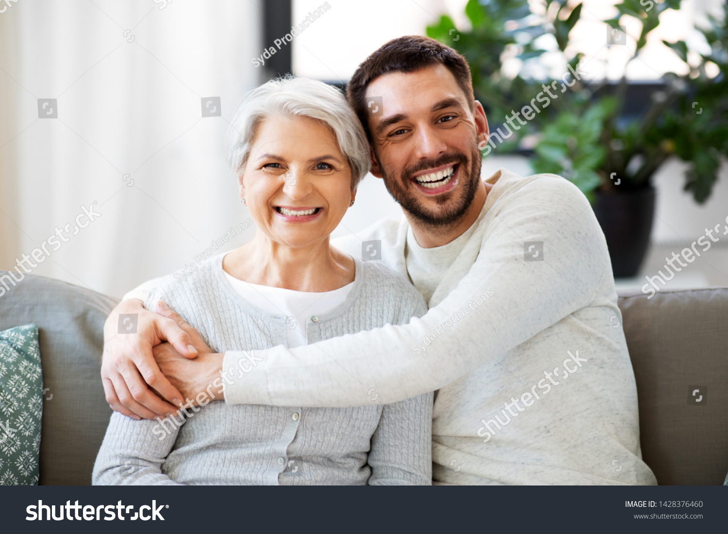 family, generation and people concept - happy smiling senior mother with adult son hugging at home #1428376460