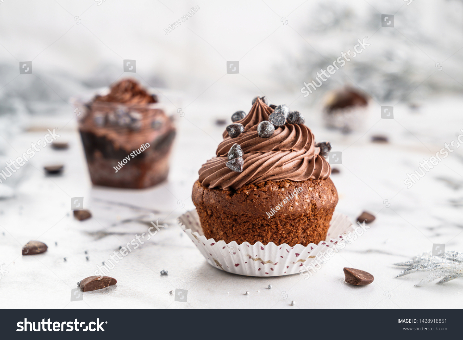Cupcakes or muffins with chocolate cream and candy on light marble background. Holiday cake celebration, delicious dessert, close up #1428918851