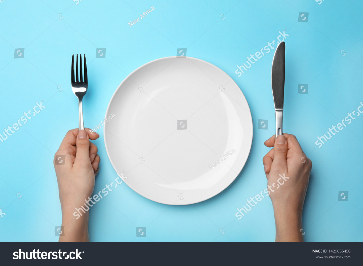 Woman with fork, knife and empty plate on color background, top view #1429055450