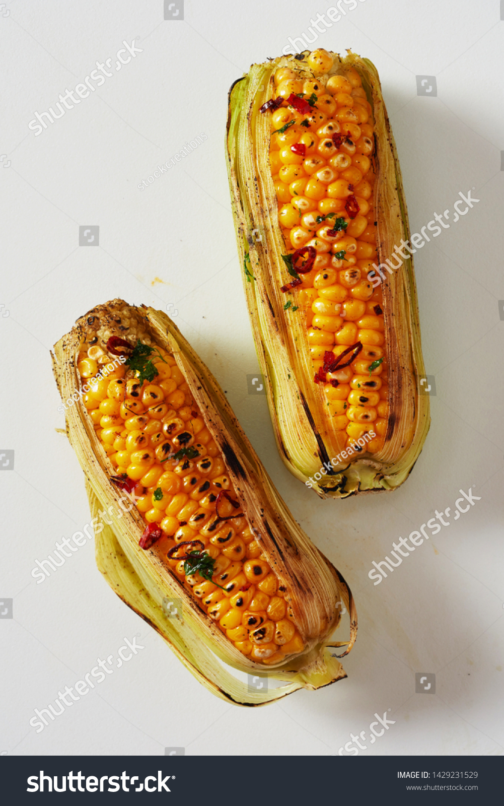 Spicy grilled corn on the cob seasoned with chili from a summer barbecue viewed from above on white in a healthy diet and seasonal cuisine concept #1429231529