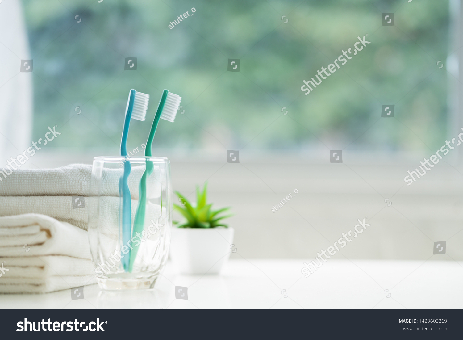 The toothbrushes in a glass and white towels with copy space in bathroom  #1429602269