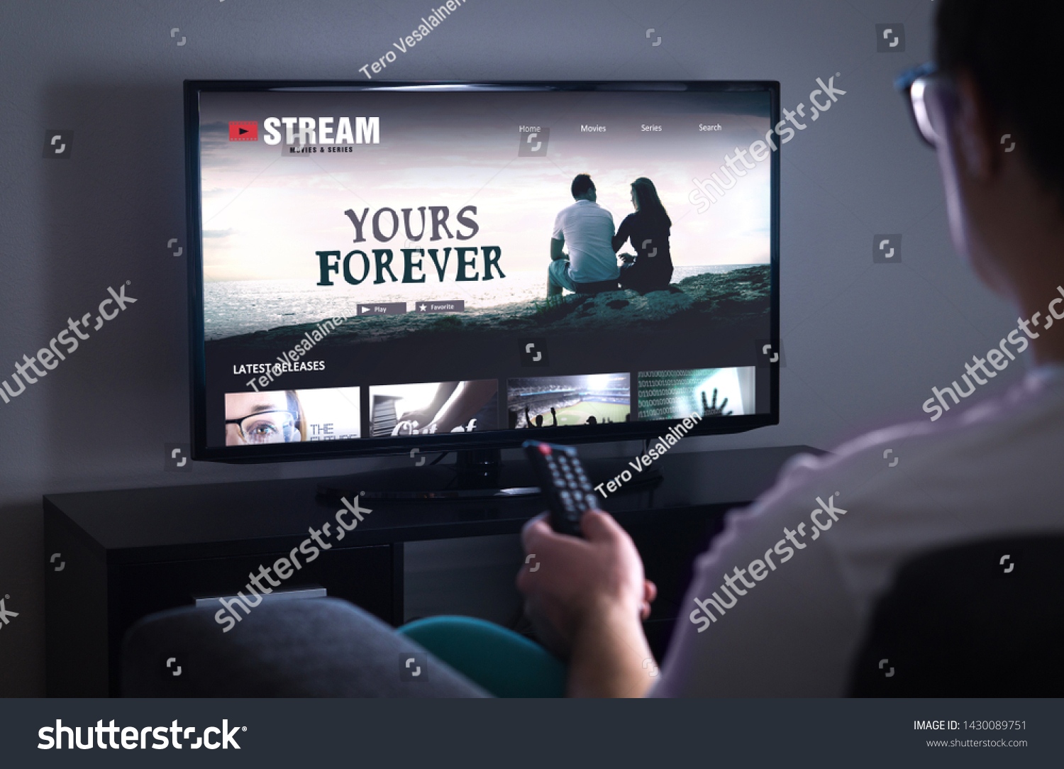 Online movie stream service in smart tv. Streaming series with on demand video (VOD) service in television. Man choosing film to watch with remote. Person sitting on couch at home late at night.