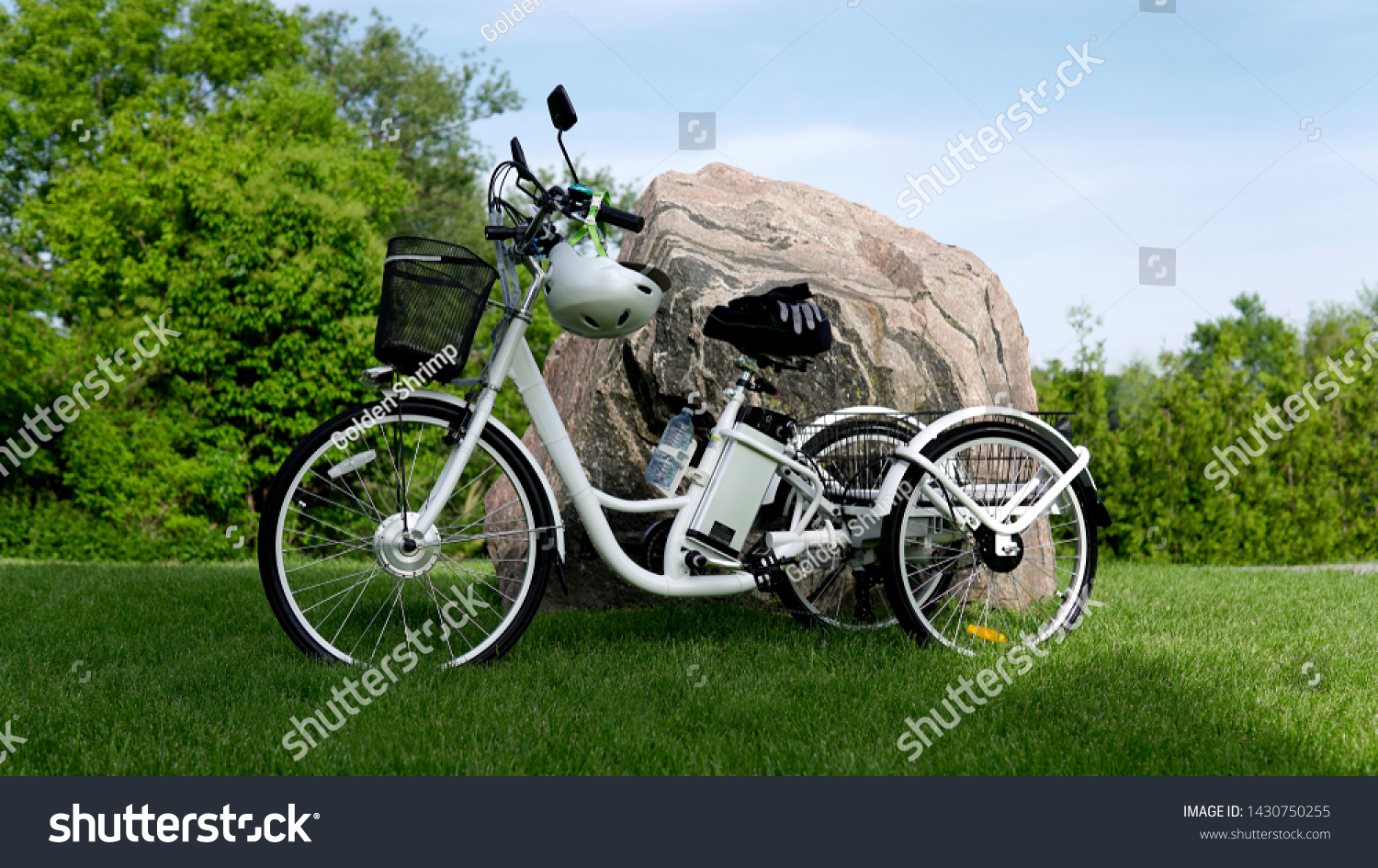Electric bicycle on the green grass with stone background on sunny summer day. Shot from the side. A lot of natural lighting. The view of the e motor, power battery gear, hamlet and gloves. #1430750255