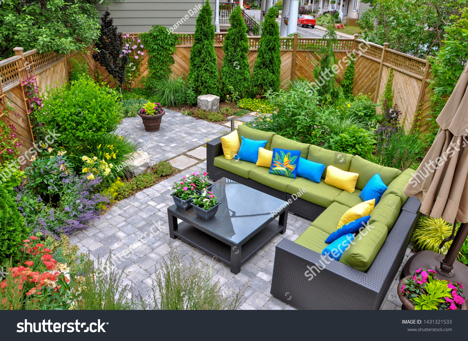 A beautiful small, urban backyard garden featuring a tumbled paver patio, flagstone stepping stones, and a variety of trees, shrubs and perennials add colour and year round interest. #1431321533