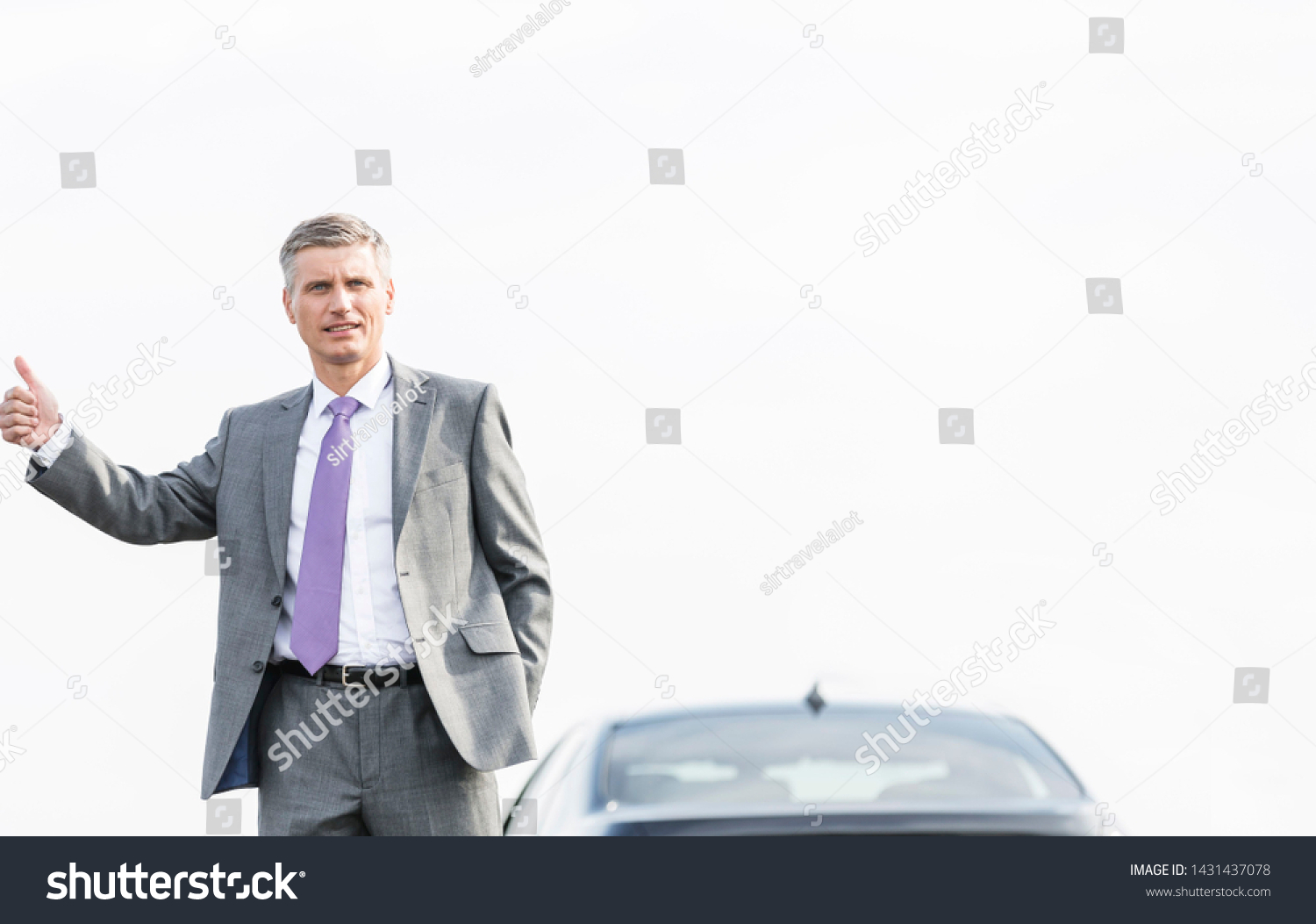 Business professional hitchhiking by breakdown car against sky #1431437078