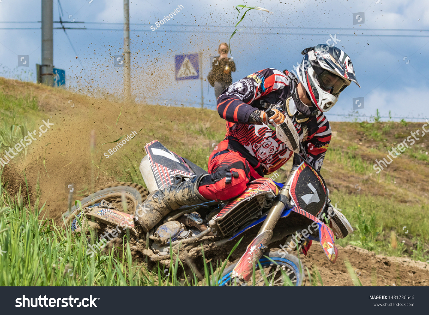 Motocross. Motorcyclist rushes along a dirt road, dirt flies from under the wheels. Green vegetation and blue sky.  Close-up. Active extreme rest. #1431736646