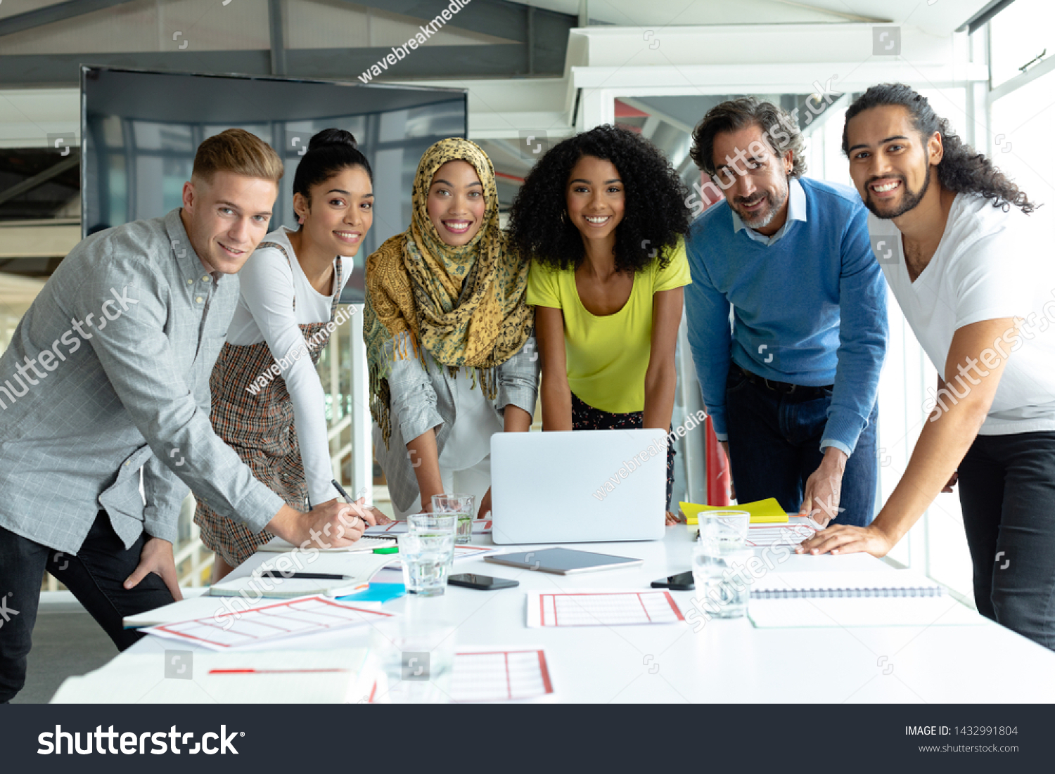 Front view of diverse business people looking at camera while working together at conference room in a modern office #1432991804