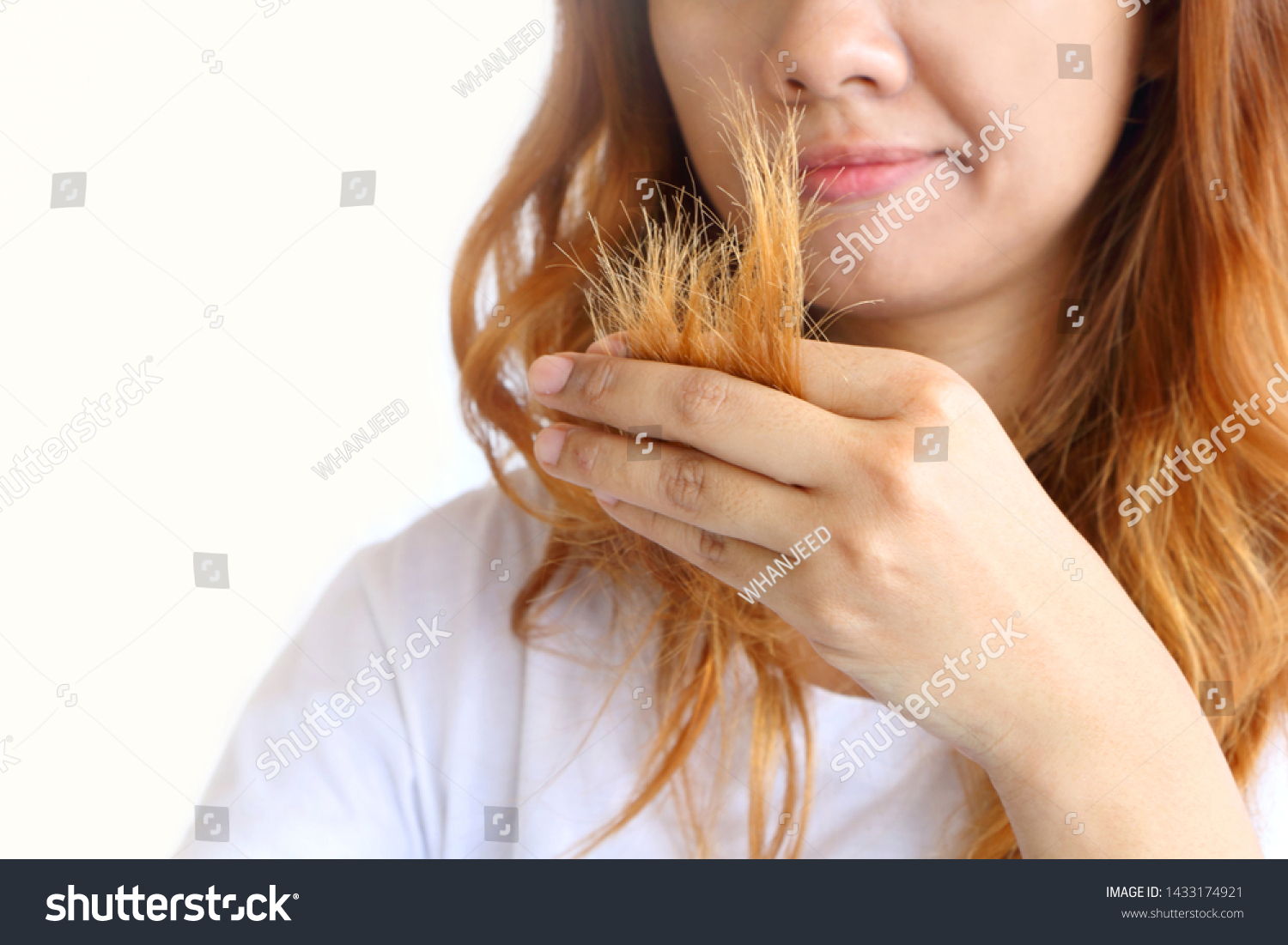 Asain woman holding her long hairs that make color treatments. The hairs maybe have problem breakage (split end) .Should care or cut end of hairs. On white background. #1433174921