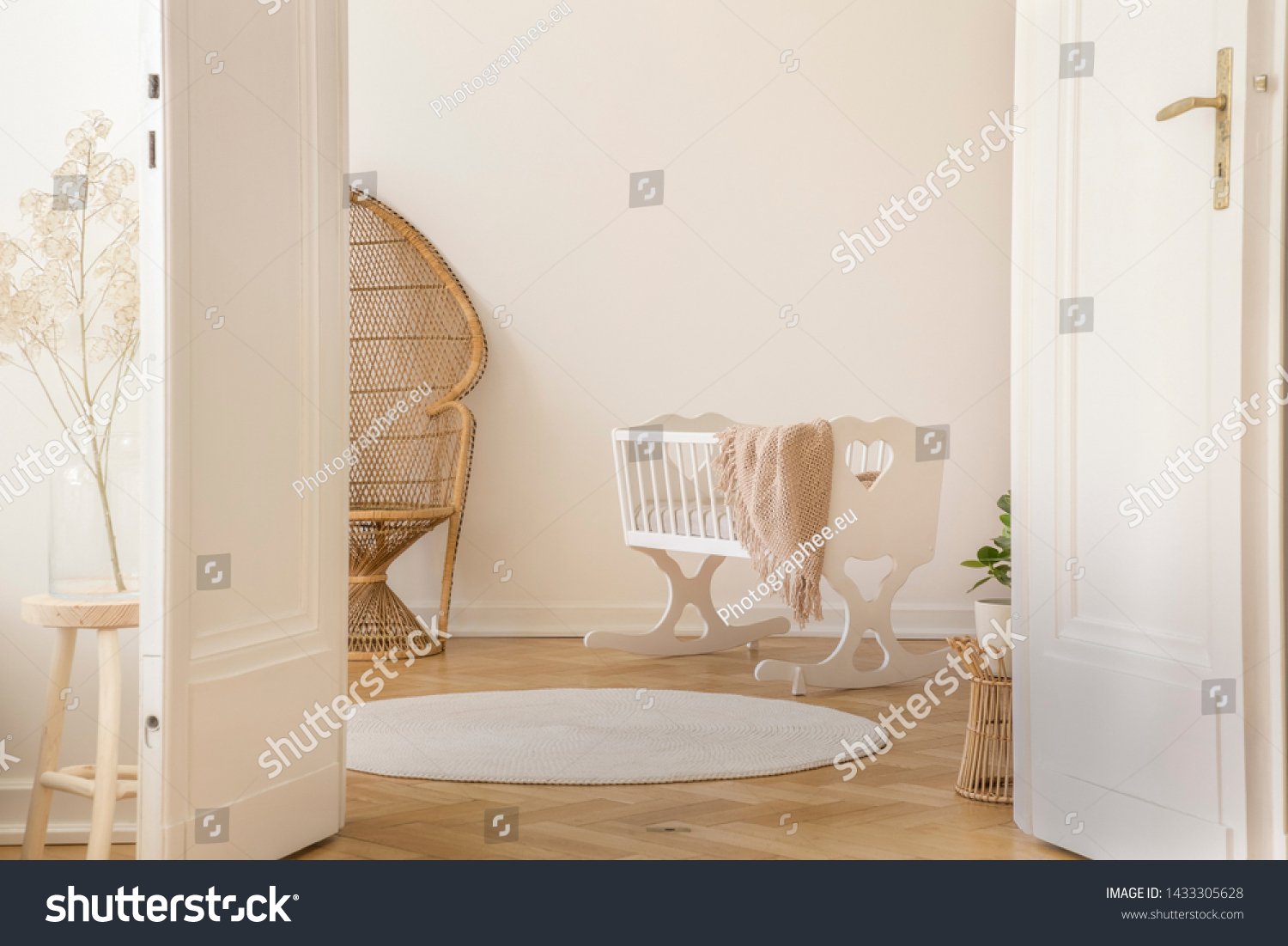 White open double door in elegant apartment with nursery designed with white crib and wicker peacock chair, real photo with copy space #1433305628