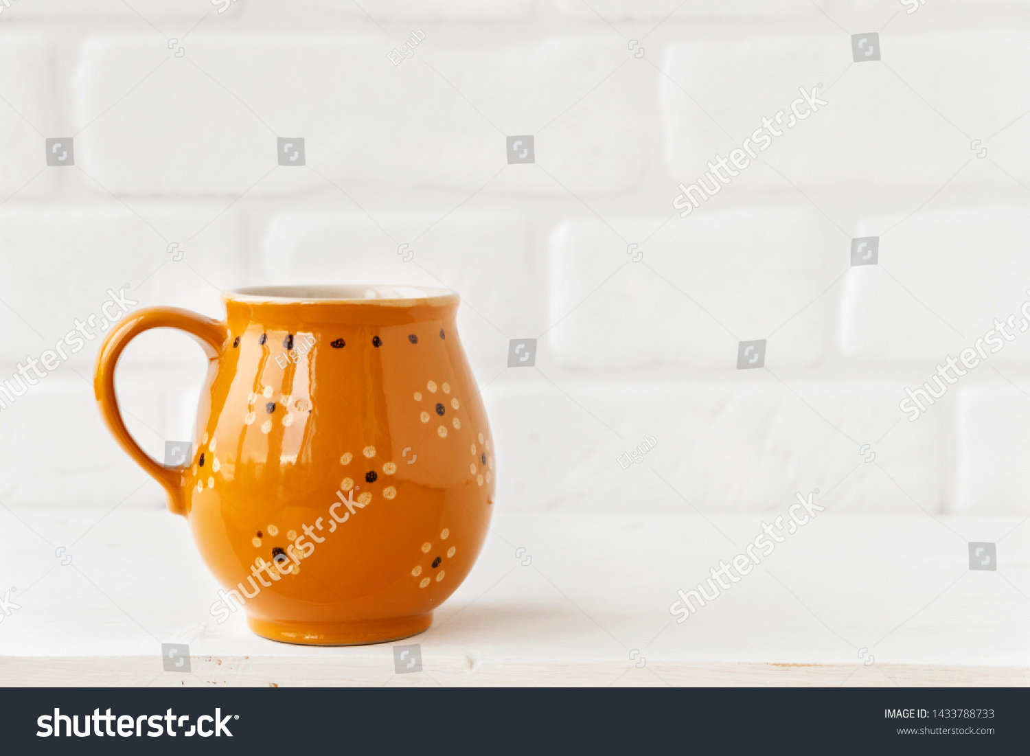 Brown rustic mug with flowers on white brick wall background. Copy space #1433788733