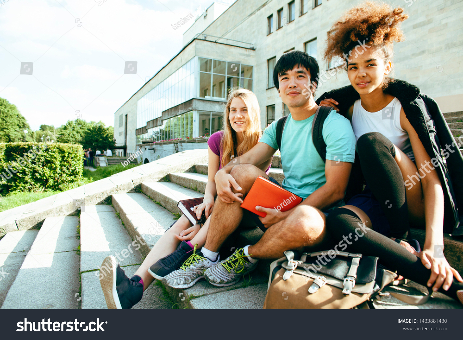 cute group of teenages at the building of university with books huggings, diversity nations students lifestyle #1433881430