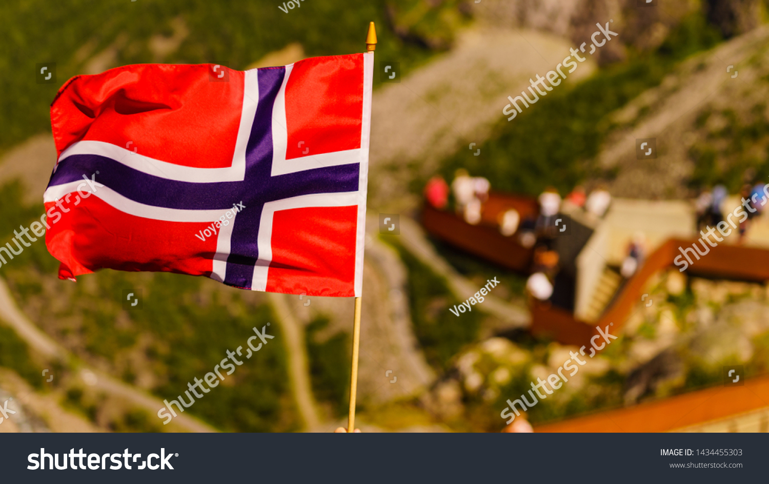Trollstigen mountain road landscape in Norway, Europe. Norwegian flag waving and many tourists people on viewing platform in background. National tourist route. #1434455303