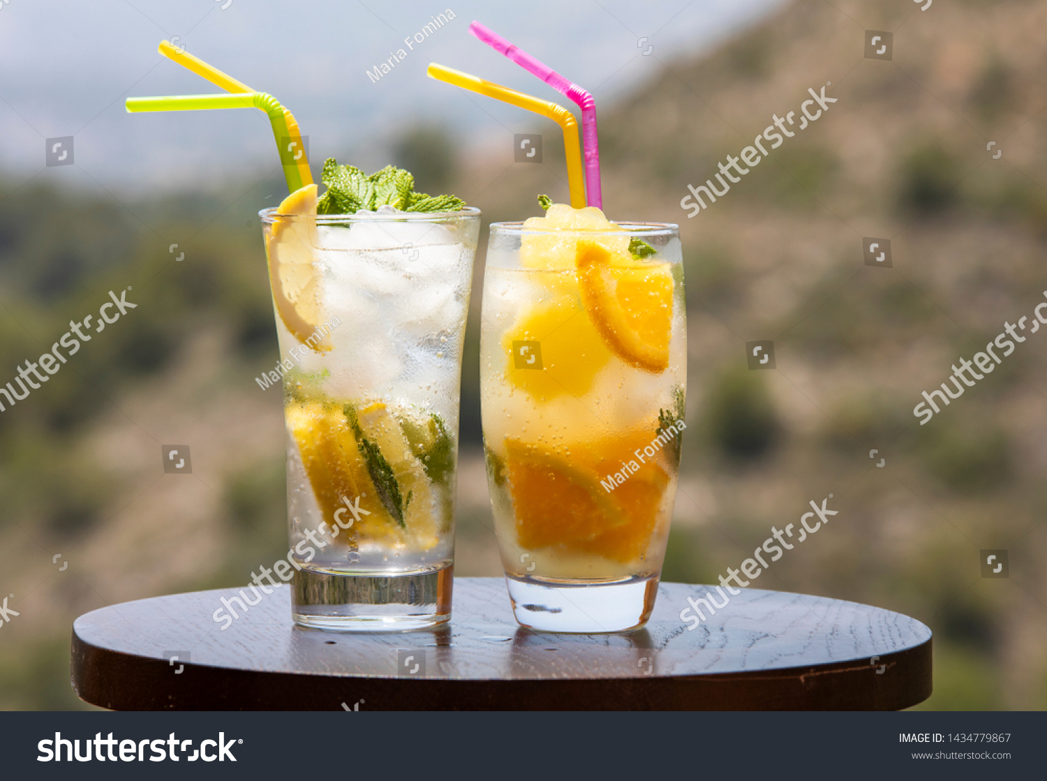 Drinks Refreshing. Bright summer refreshments made from juicy fruits. Two glasses of citrus fruits with ice and mint on the background of the hill #1434779867