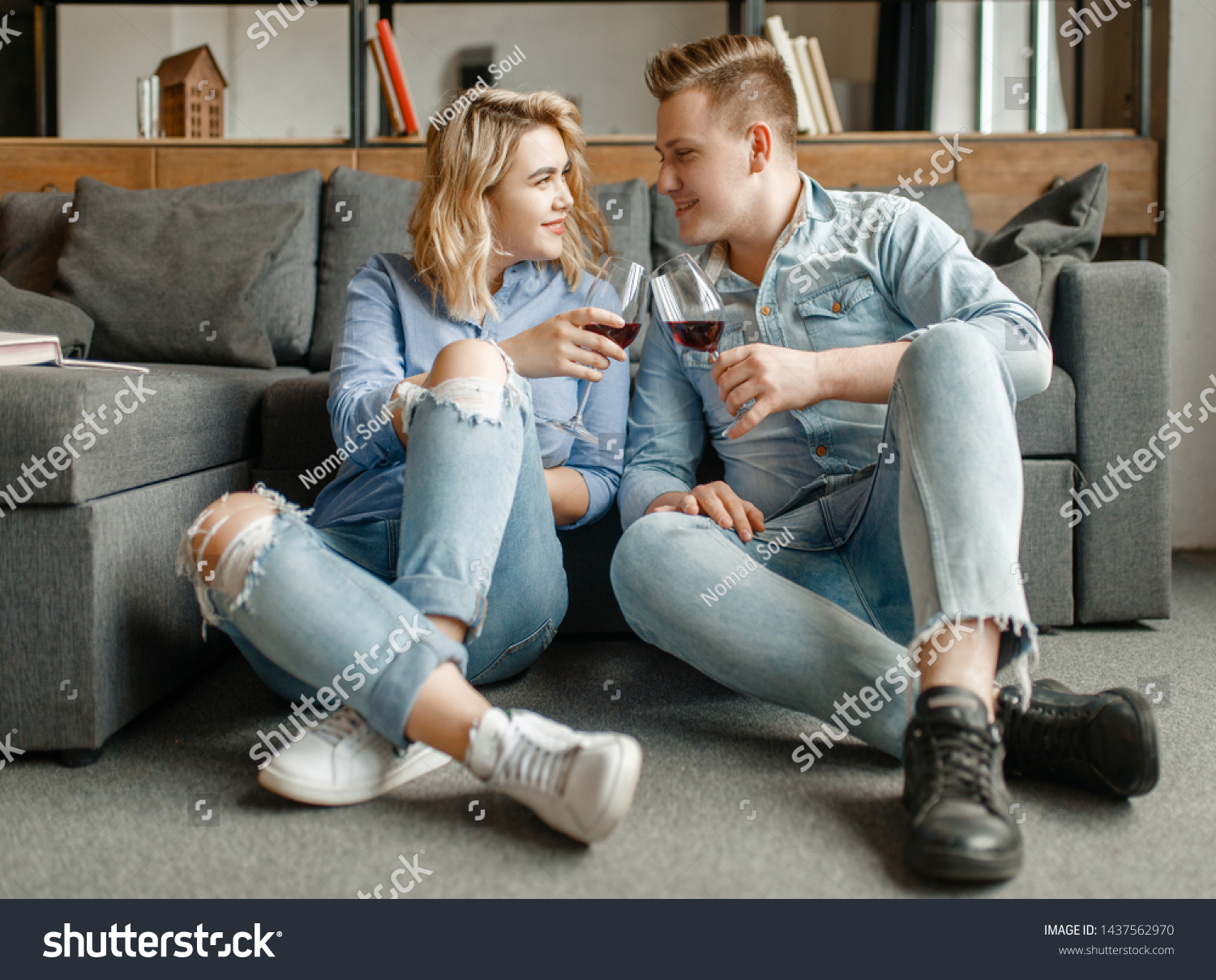 Couple drinks red wine on the floor at the couch #1437562970