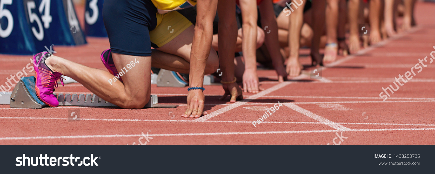 Group of male track athletes on starting blocks.Hands on the starting line.Athletes at the sprint start line in track and field #1438253735