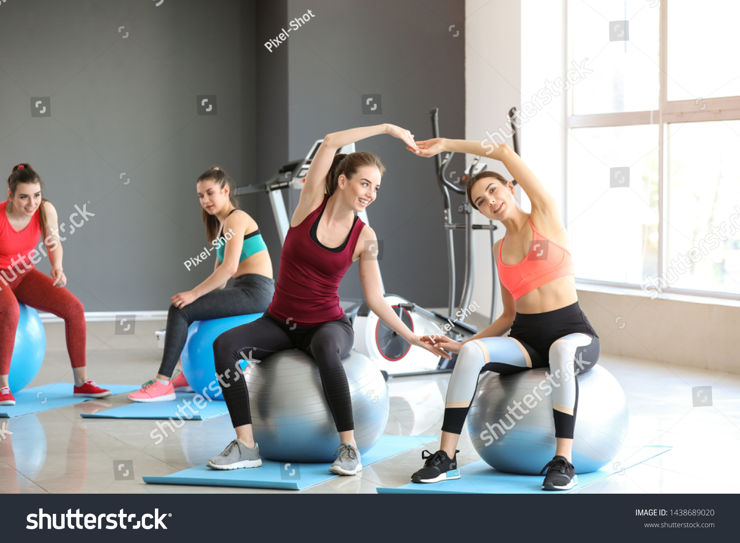 Young sporty women doing exercises with fitballs in gym #1438689020