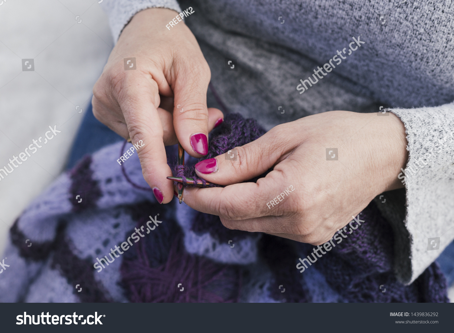 Close-up of woman knits woolen clothes with knitting needles #1439836292