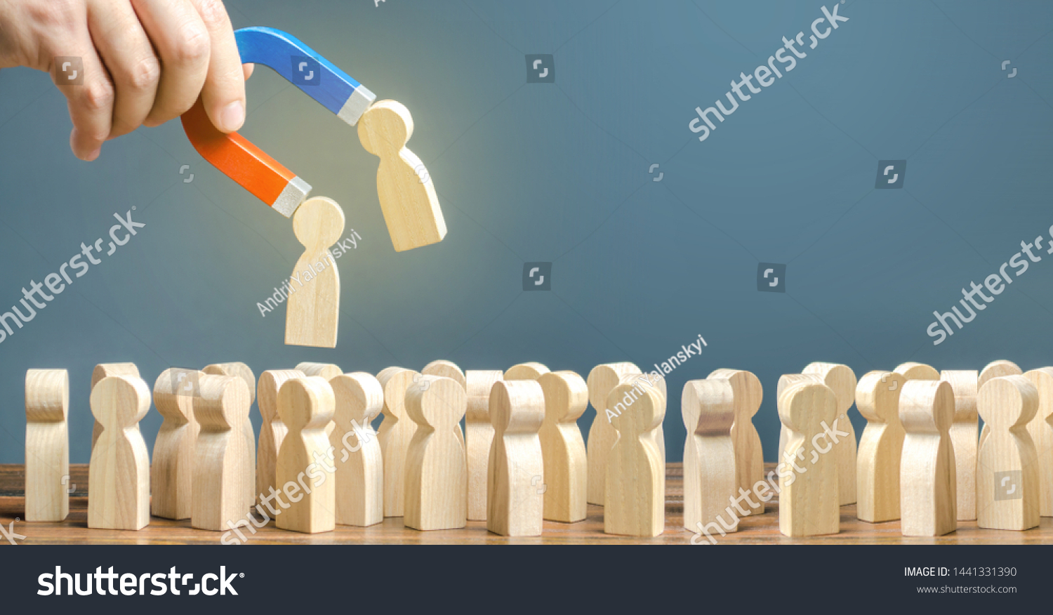 Businessman with a magnet pulls wooden figures of people out of big crowd. Recruiting workers. Formation of a new team. Search for required people and workers with the necessary talents and skills #1441331390