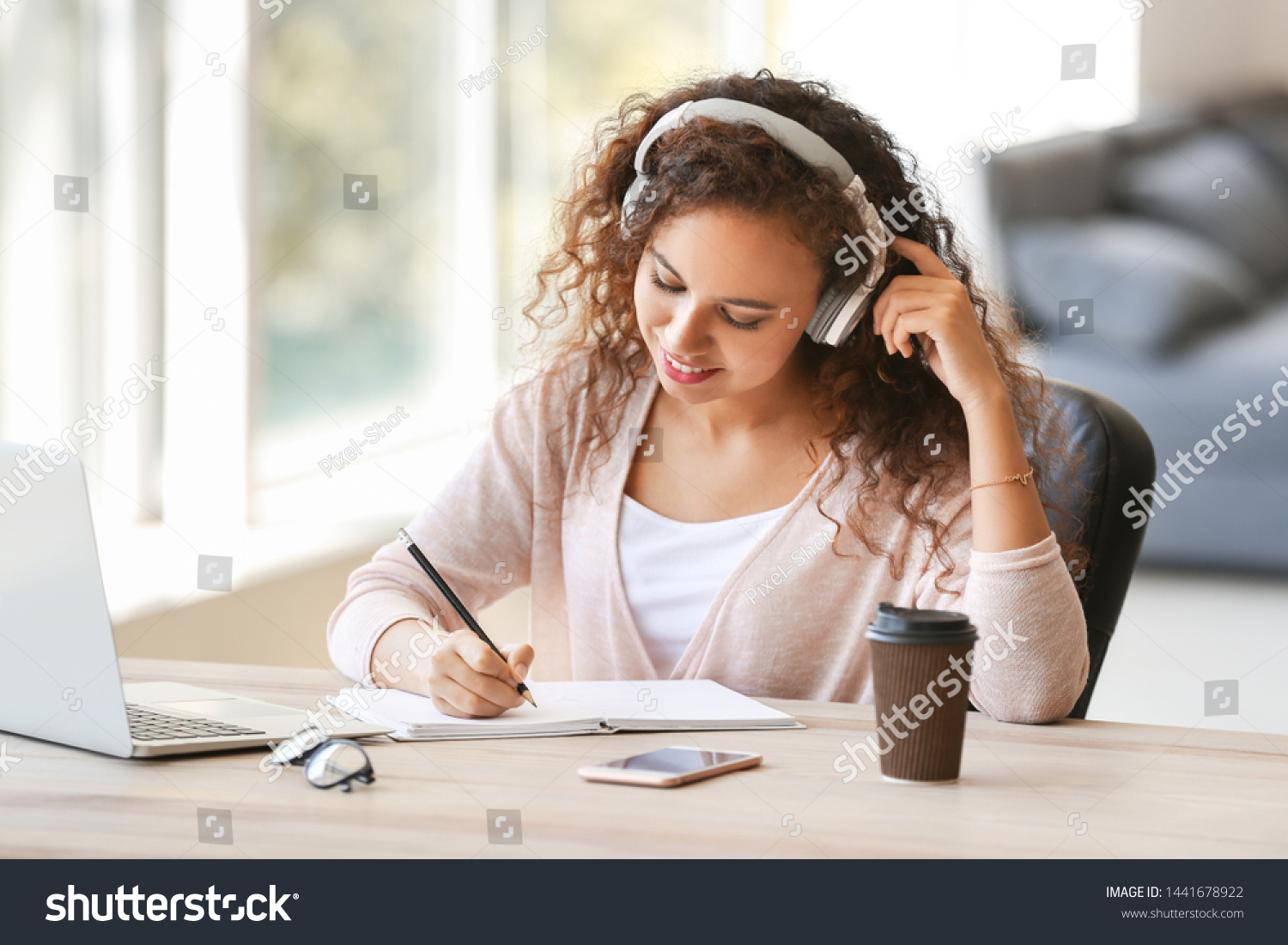 Young African-American student listening to music while preparing for exam #1441678922