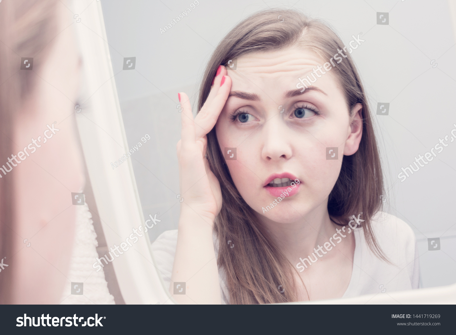Sleepy young woman, reflection in the mirror, girl is upset because of the first wrinkles looks in the mirror #1441719269