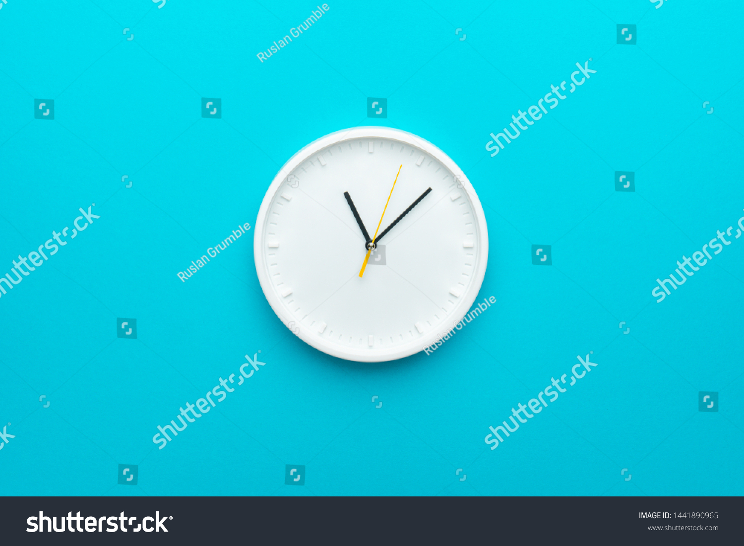 White wall clock with yellow second hand hanging on the wall. Minimalist flat lay image of plastic wall clock over blue turquiose background with copy space and central composition. #1441890965