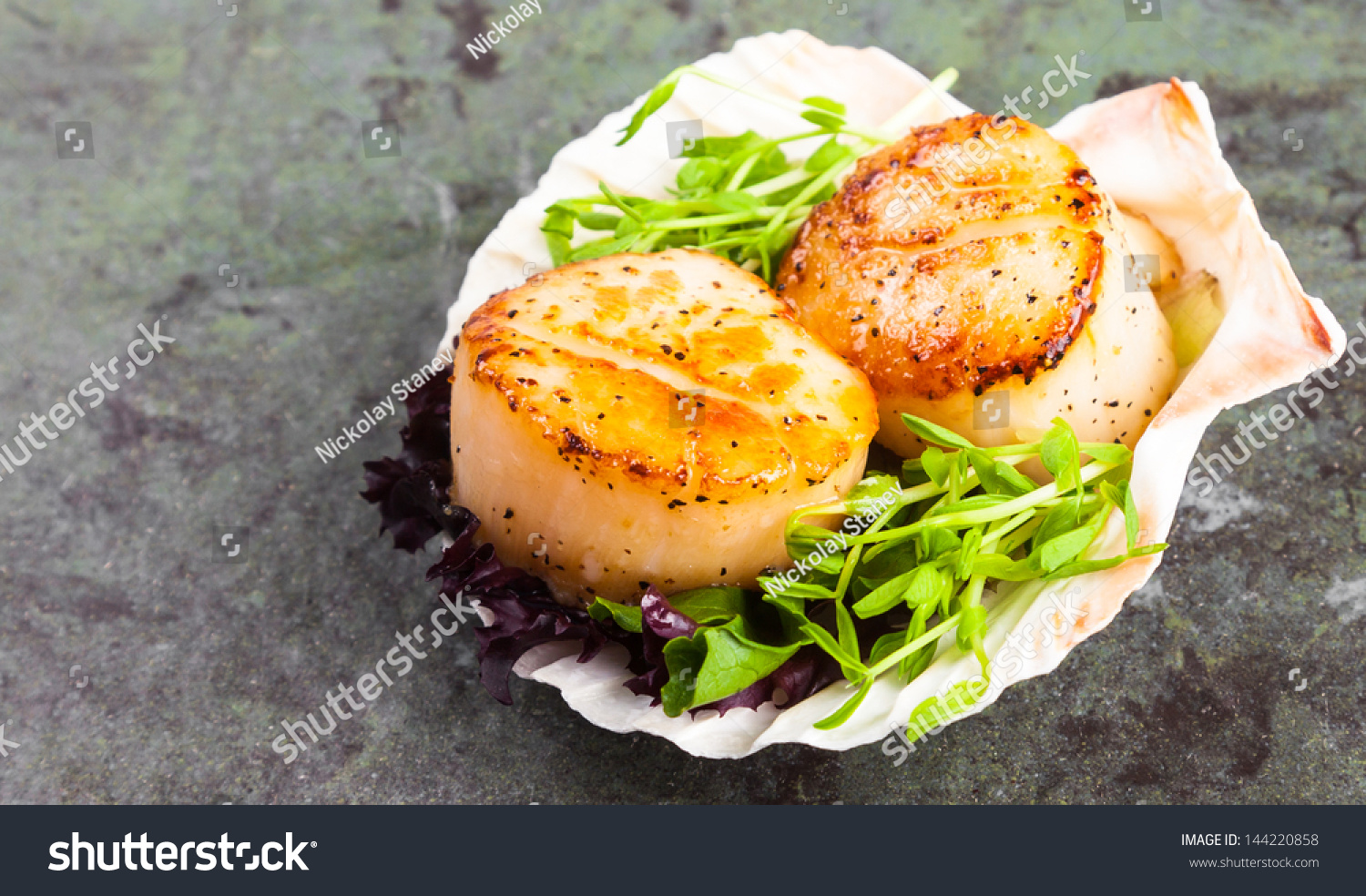 Pan seared scallops with garnish on a stone plate.. #144220858
