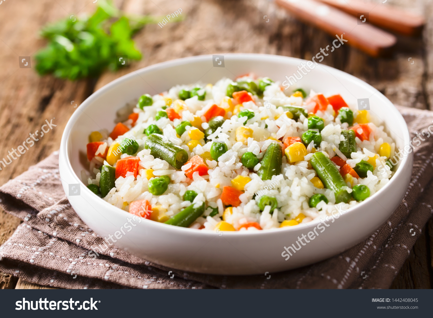 Cooked white rice mixed with colorful vegetables (onion, carrot, green peas, corn, green beans) in white bowl (Selective Focus, Focus in the middle of the dish) #1442408045