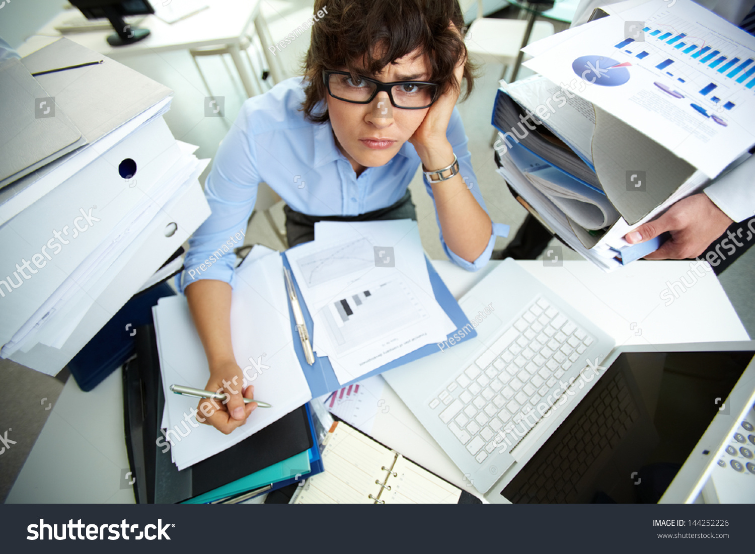 Perplexed accountant doing financial reports being surrounded by huge piles of documents #144252226