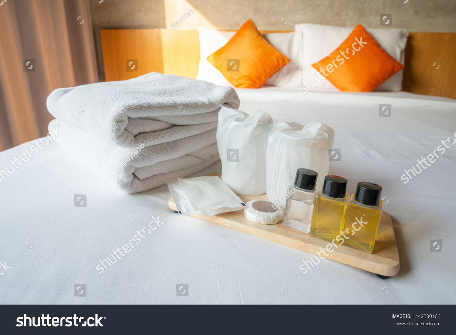 Set of hotel amenities (such as towels, shampoo, soap, drinking glass etc) on the bed. Hotel amenities is something of a premium nature provided in addition to the room when renting a room. #1442530166