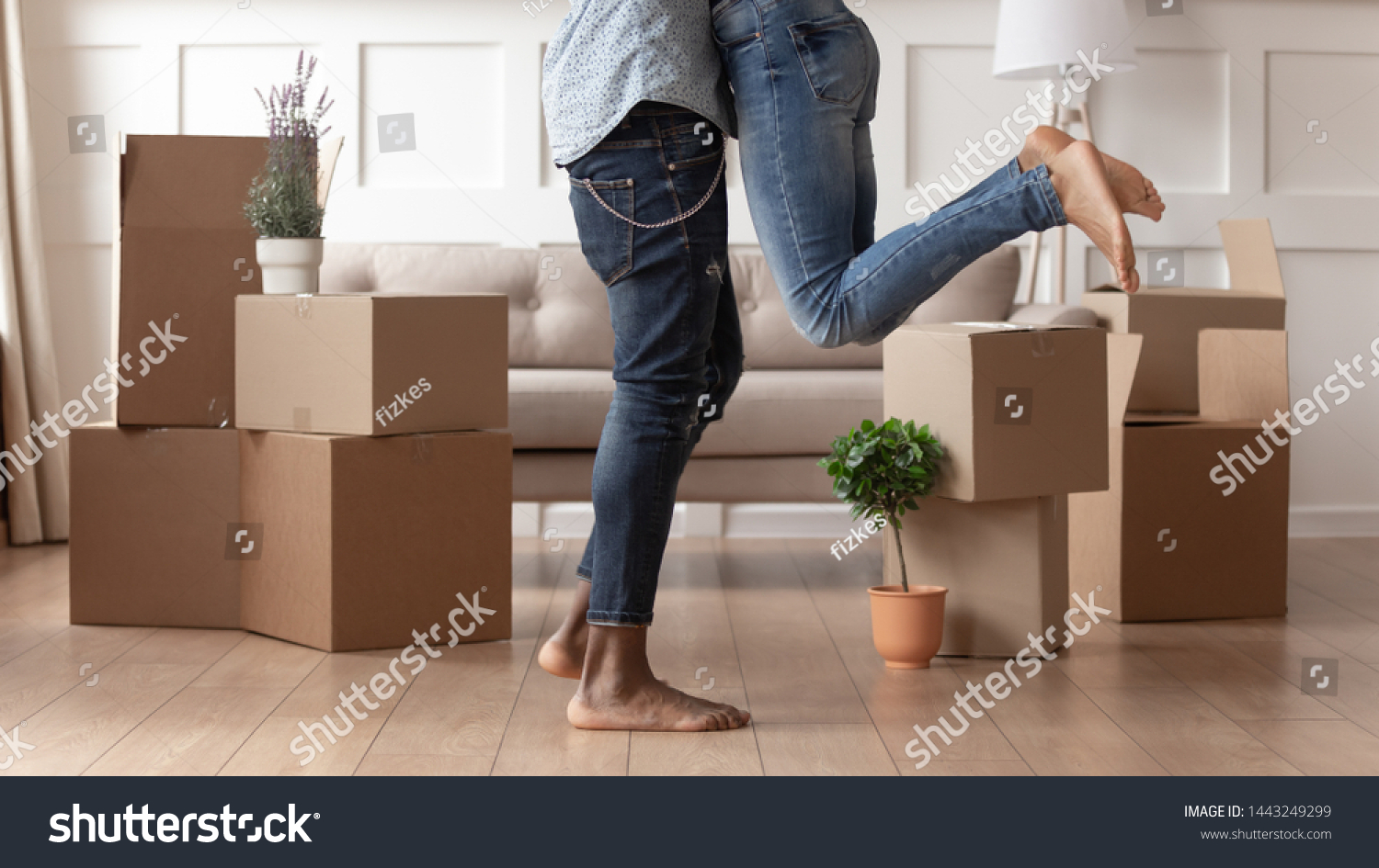 Close up young husband in jeans lift wife surrounded by cardboard boxes excited to move in new flat, happy african American couple have fun hug feel euphoric relocating together to own house #1443249299