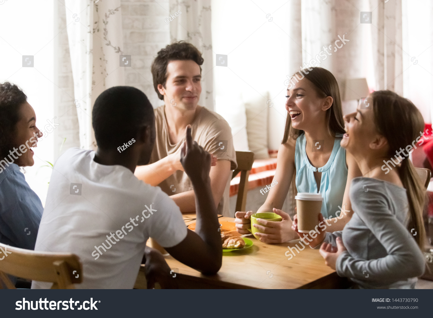 Mixed race happy young people gathering in cafe, sitting at table, chatting, talking, drinking coffee, spending funny time, diverse millennial guys and girls, students or best friends meeting. #1443730790
