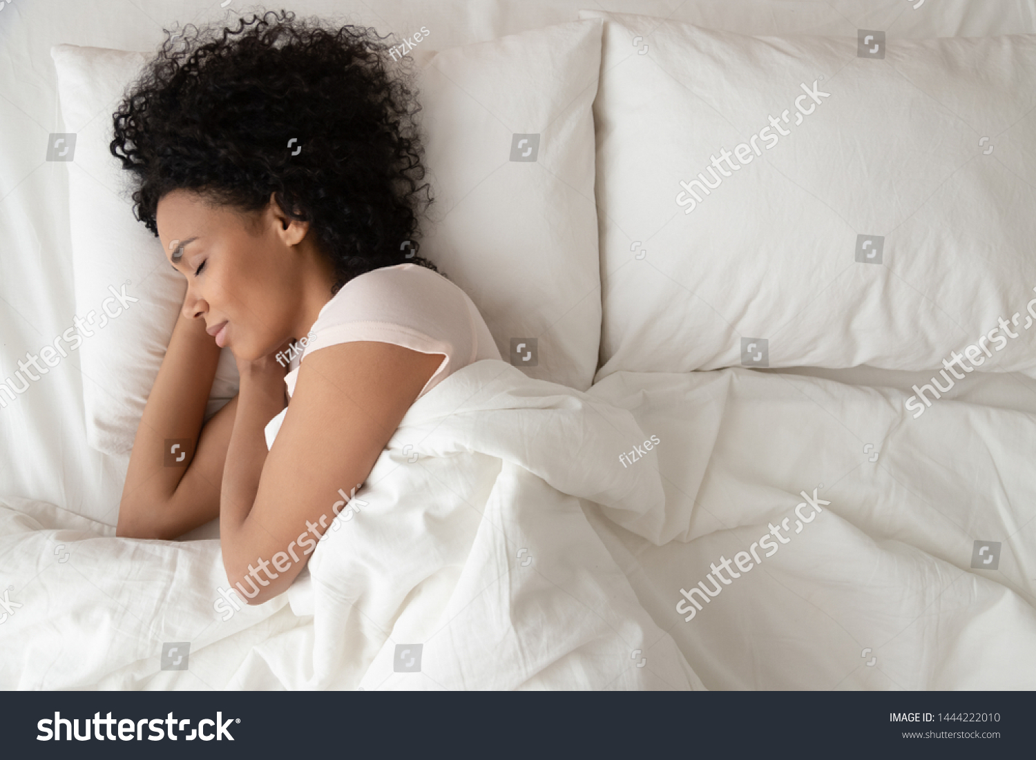 Serene calm african american woman sleeping in comfortable bed lying on soft pillow orthopedic mattress, peaceful young black lady resting covered with blanket on white sheets in bedroom, top view #1444222010
