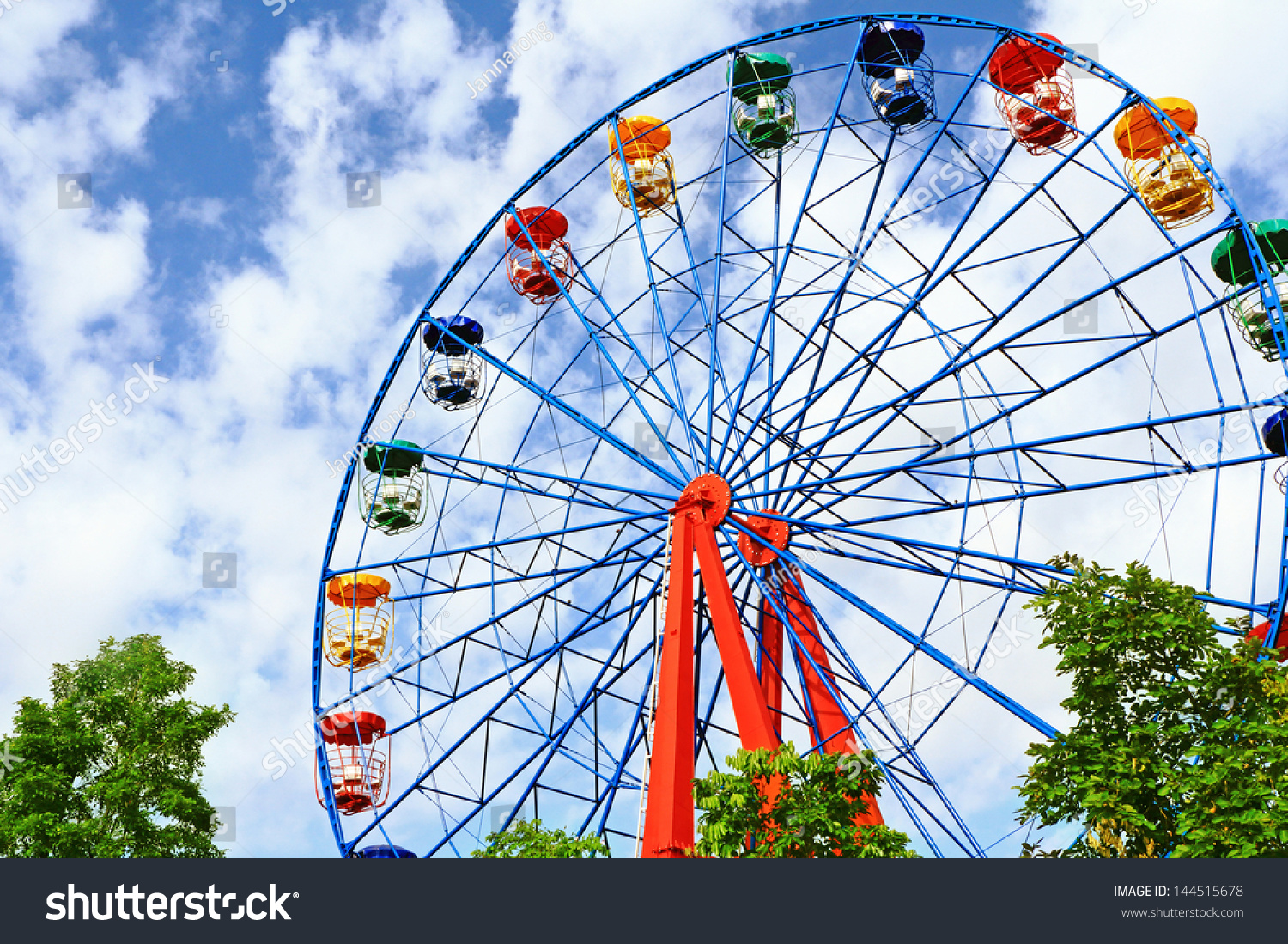 Giant ferris wheel against blue sky and white cloud which mean an amusement-park or fairground ride consisting of a giant vertical revolving wheel with passenger cars suspended on its outer edge #144515678