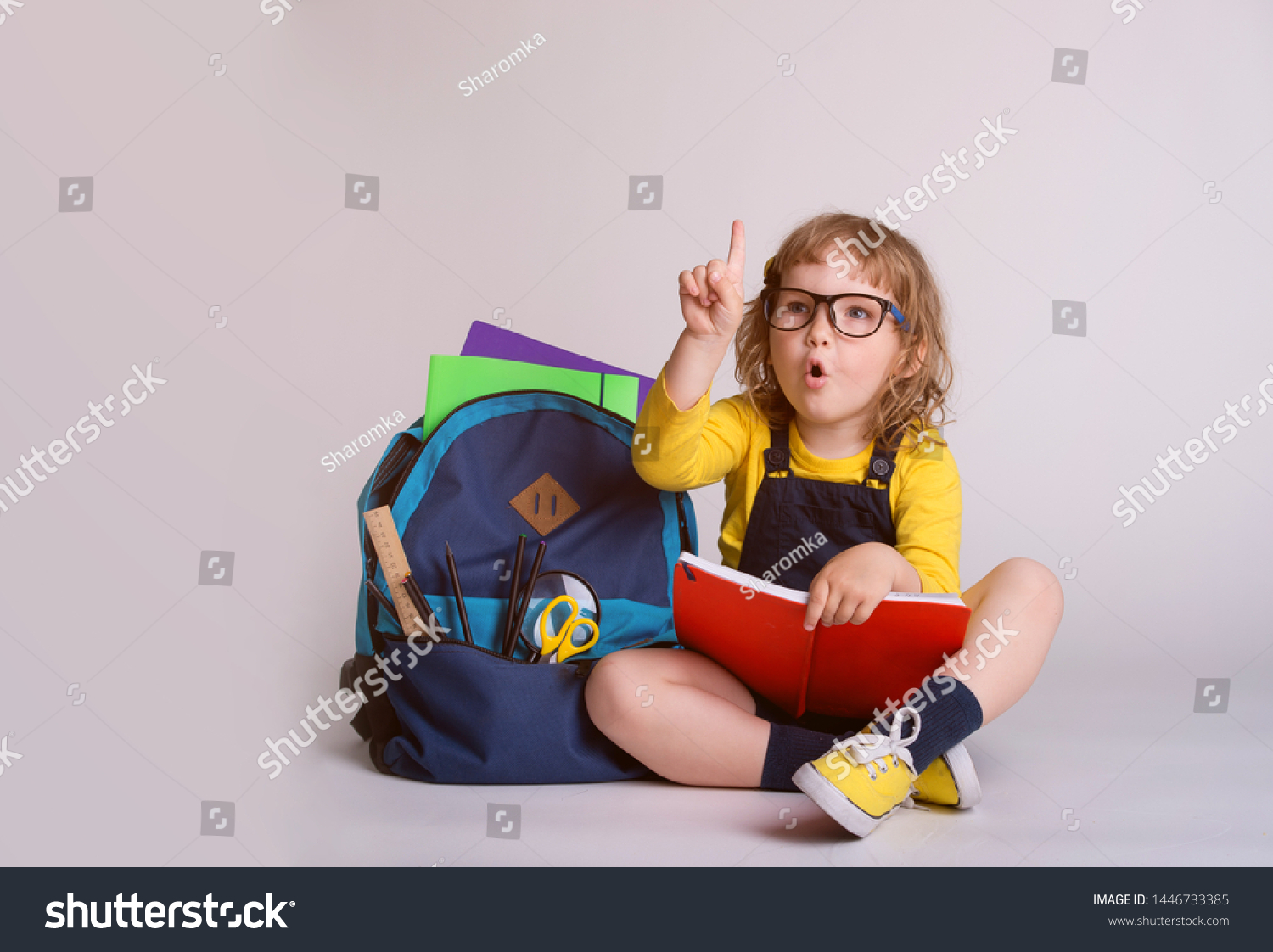 Children go back to school. Little happy  girl doing homework at home with backpack full of books, pencils. Pupil reading a book, writing and painting.  Kid is drawing. Child in glasses.  #1446733385