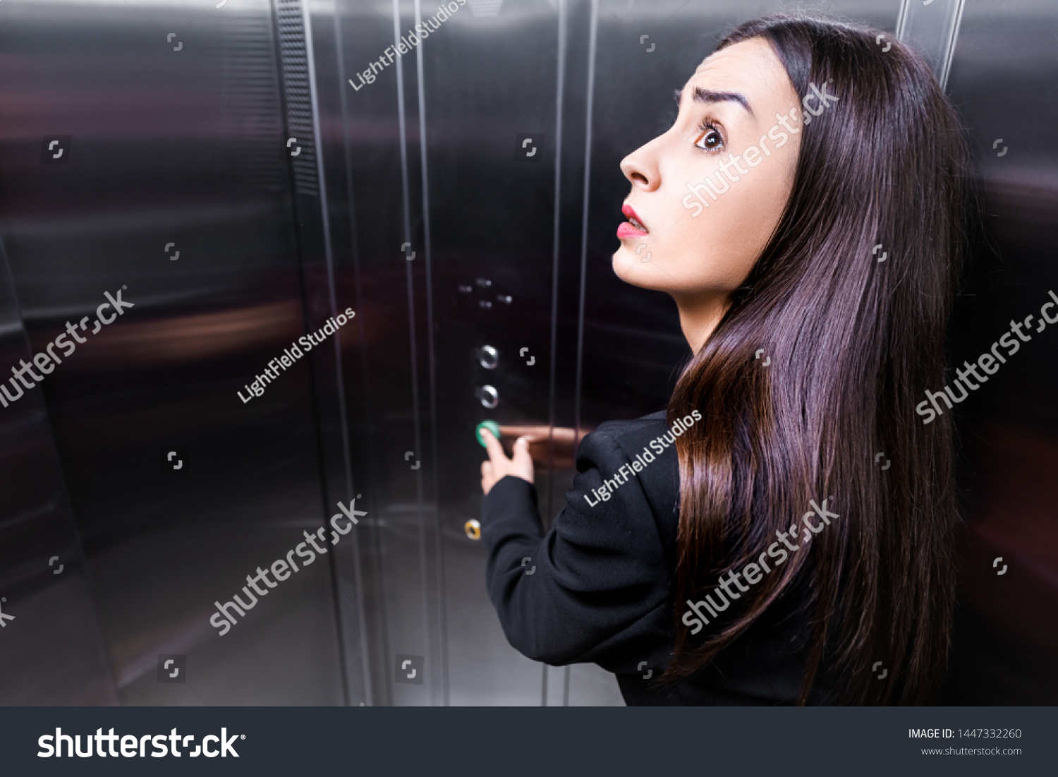 scared businesswoman, suffering from claustrophobia, looking up while pushing button in elevator #1447332260