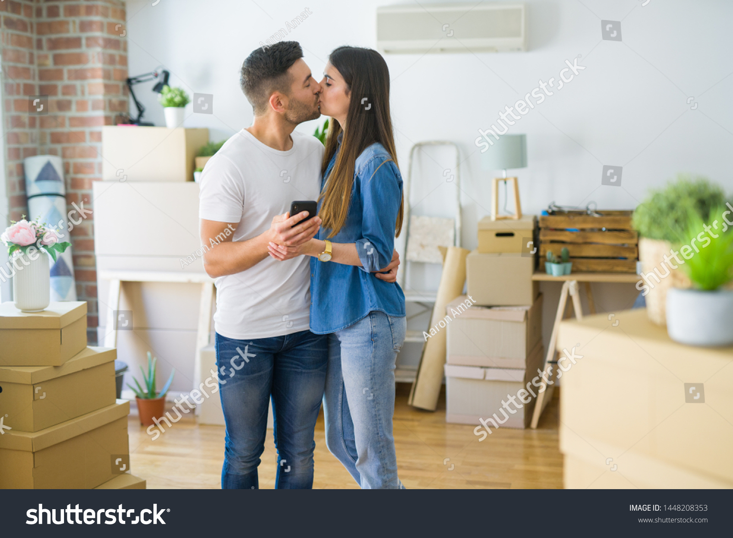 Young couple moving to a new house, using smartphone smiling very happy for new apartment #1448208353