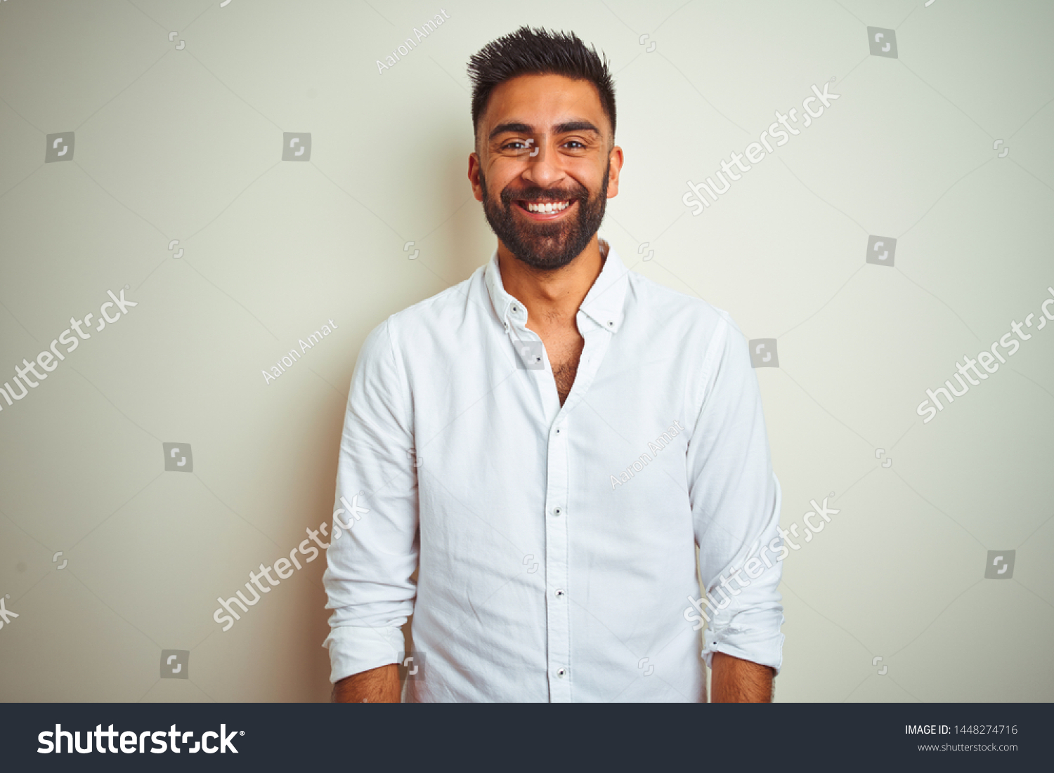 Young indian man wearing elegant shirt standing over isolated white background with a happy and cool smile on face. Lucky person. #1448274716
