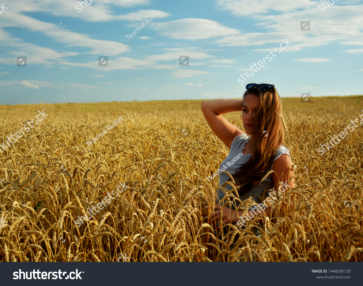 Young beautiful girl stands on a field in wheat under sunlight. #1448336120