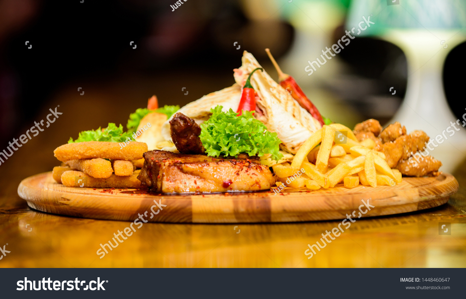 Restaurant food. Wooden board with lot french fries fish sticks burrito and meat steak served with salad. Pub menu snack. High calorie snack for group friends. Tasty delicious snacks. Snack for beer. #1448460647