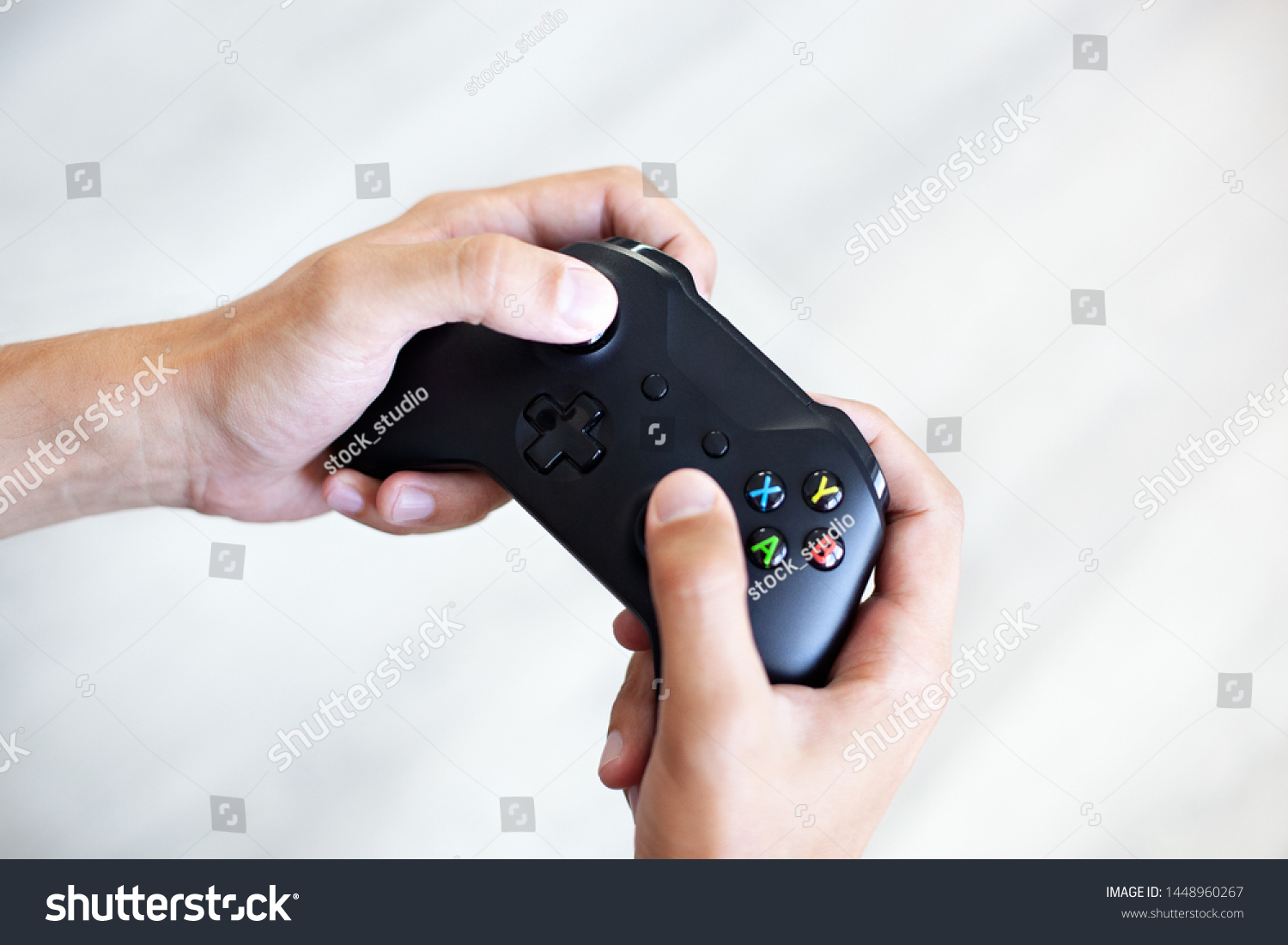Black joystick in hands isolated on white background. The guy is playing on the console. Computer gaming technology play competition videogame control confrontation concept. Cyberspace symbol
 #1448960267