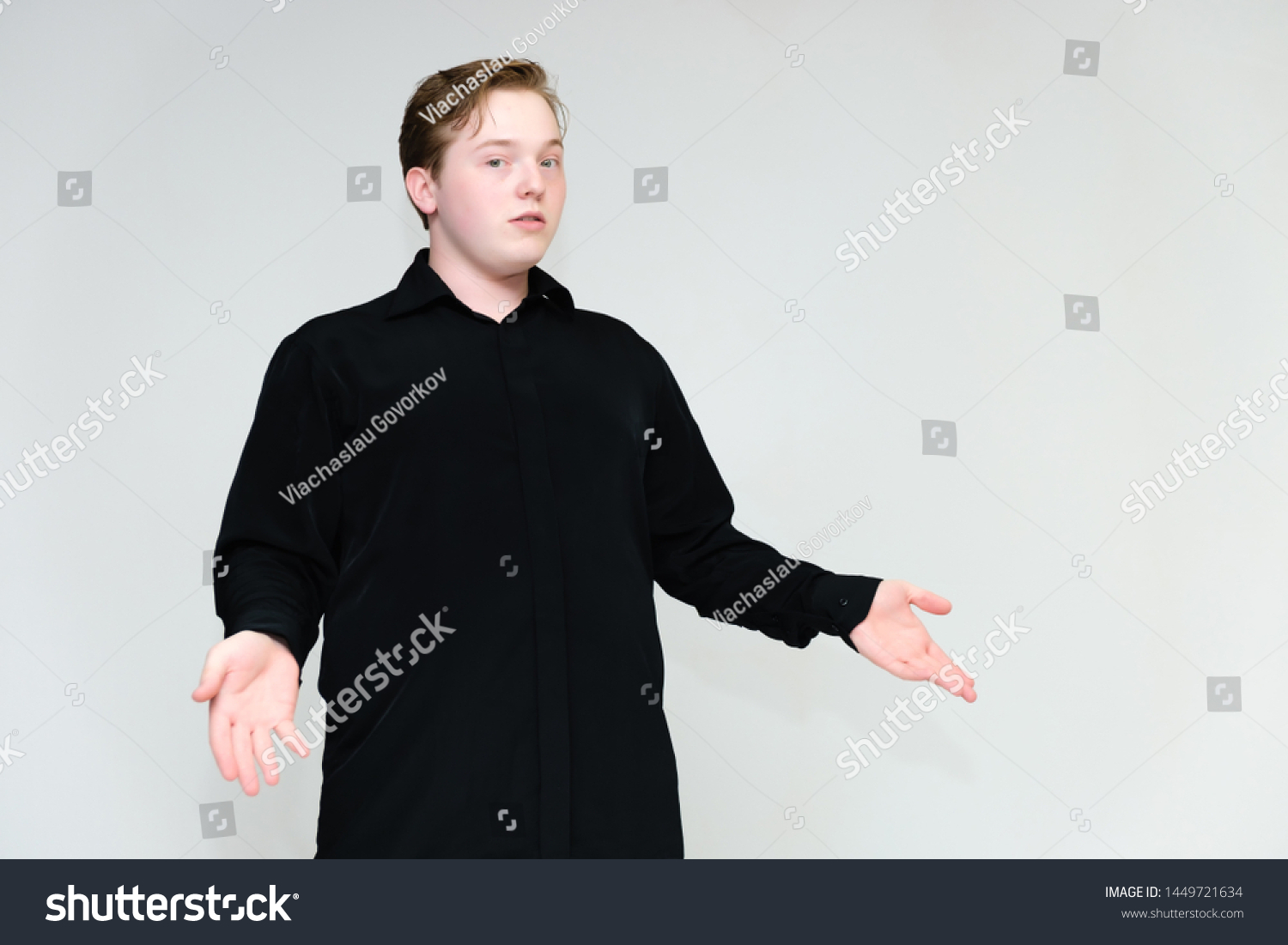 Portrait to the waist on a white background of a handsome young man in a black shirt. stands directly in front of the camera in different poses, talking, showing emotions, showing hands. #1449721634