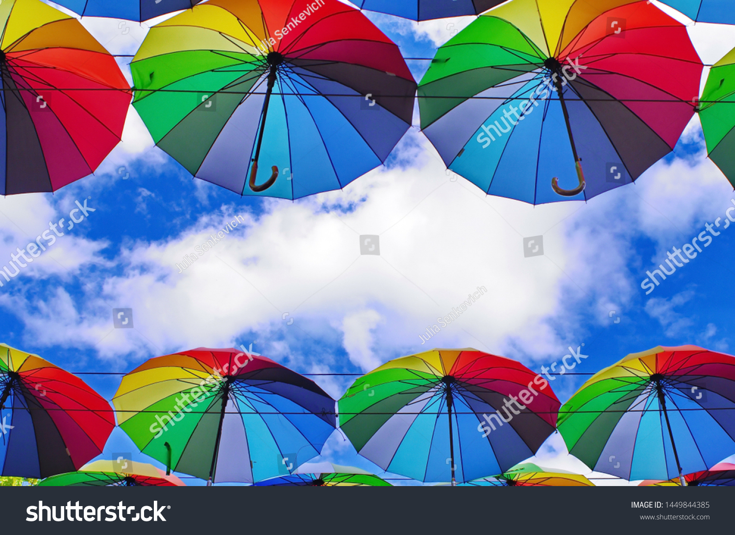 colorful rainbow bright umbrellas  street decoration against a blue sky with fluffy clouds #1449844385