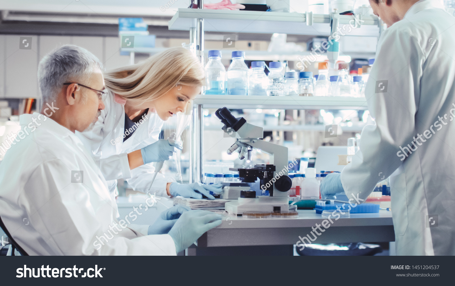 Group of Research Scientists in White Coats are Working with Microscope in a Modern High-Tech Laboratory. Genetics and Pharmaceutical Studies and Researches. #1451204537