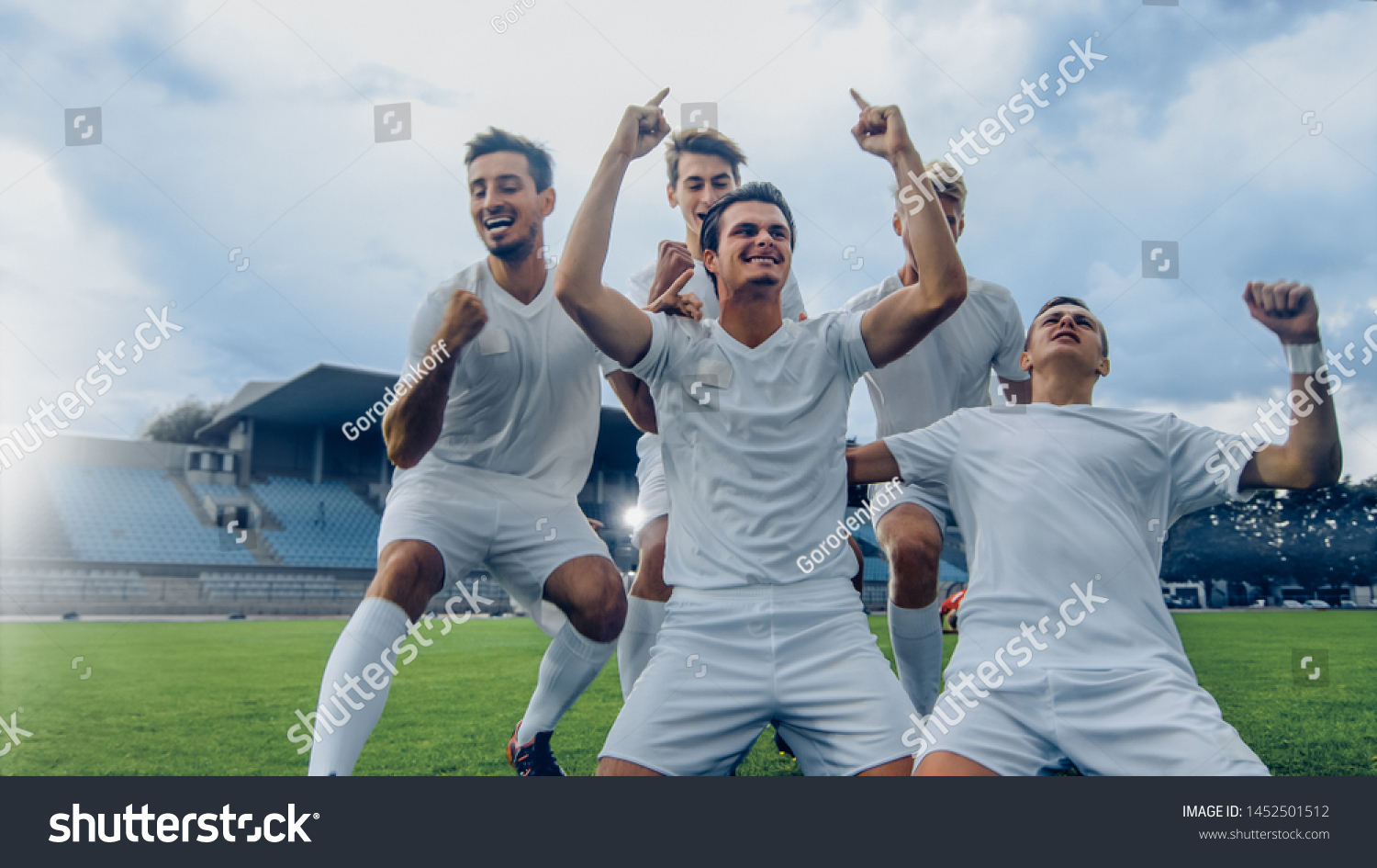 Captain of the Soccer Team Stands on His Knees Celebrates Awesome Victory, Makes YES Gesture Champion Team Joins Him. Successful Happy Football Players Celebrate Victory. #1452501512